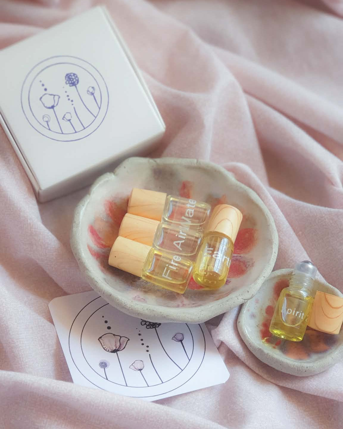 Small containers with yellow liquid on a pink fabric background